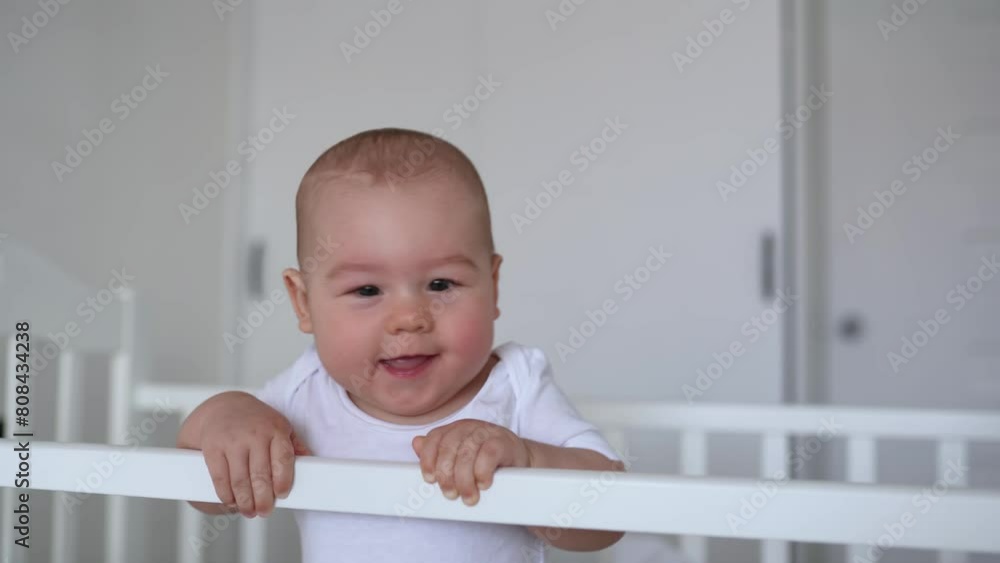 the child smiles at the camera and laughs. happy family child dream concept. baby standing in crib the child smiles at the camera and laughs. happy family child dream concept. baby standing in crib
