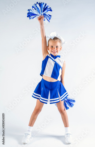 Εκτύπωση καμβά Smiling young cheerleader in a blue and white uniform holding up a pompom above