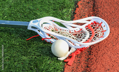 Lacrosse stick on the turf next to a ball close to the track