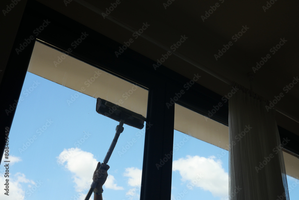 Rubber squeegee cleans a soaped window. Rubber squeegee cleans a soaped window.