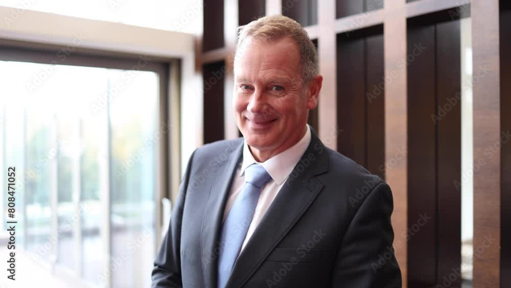 Video portrait of a mature businessman standing at the hallway of his company and smiling Video portrait of a mature businessman standing at the hallway of his company and smiling