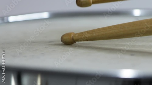 close up drumsticks tips hitting steel snare drum head against white background photo