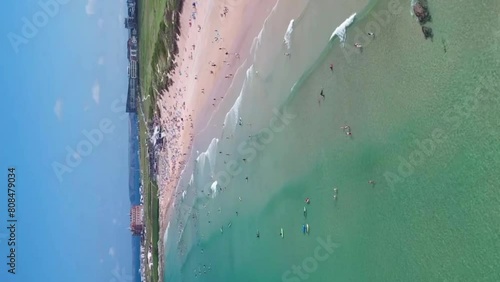 Fistral Beach with Clear Turquoise Waters with People Enjoying the Summer Sun. Aerial Dolly Shot Vertical Format Mode for Social Media Stories. photo