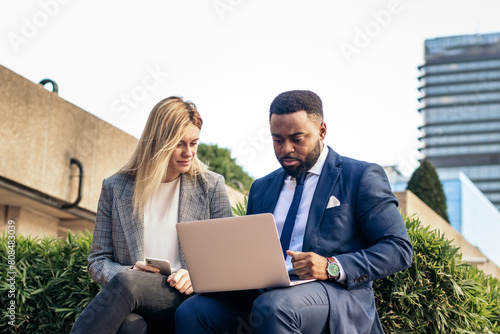 Business colleagues working with laptop outdoors