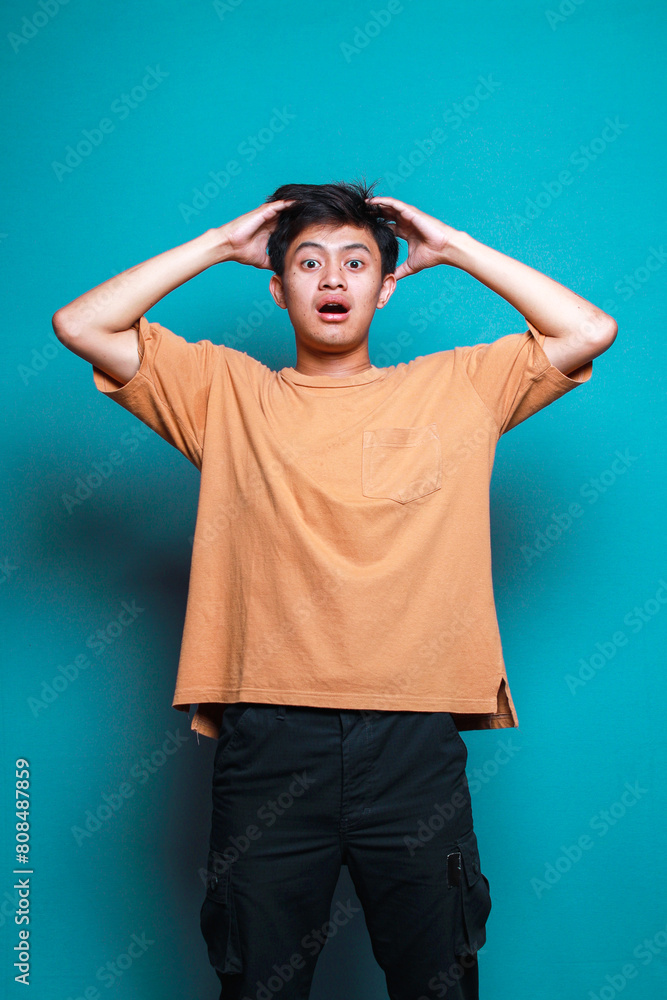 Portrait of Asian young man shocked and surprised isolated on teal background Portrait of Asian young man shocked and surprised isolated on teal background