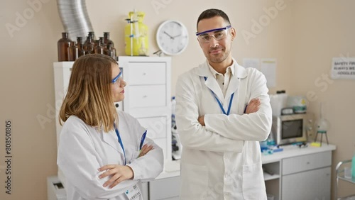 A man and woman in lab coats converse confidently in a bright laboratory, symbolizing professional teamwork. photo