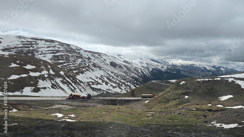 Truck on the road with the snowcaped mountain in the background and heavy clouds photo