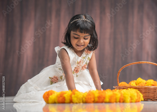 Indian festival special image cute little girl making flower decoration, Kerala Onam festival Pookalam image © sarath