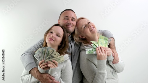 happy rich family dollars and euros in the hands of mom daughters dad father hugs them smiling happy waving money like fan on a white background a lot of money luck travel in games. kissing relatives