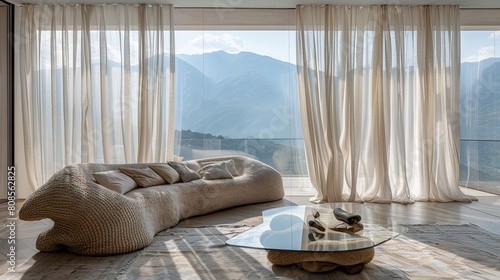 A high-end living room with a large bay window draped in sheer linen curtains, an ultra-modern glass coffee table, and a sculptural wool sofa set against a panoramic view of the mountains photo