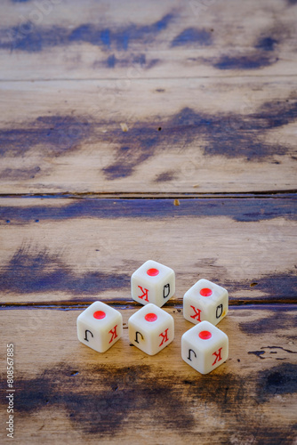Poker playing dice, with red dot, on a wooden table.