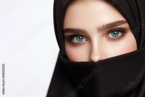 Beautiful girl in a black hijab, only her eyes are visible on a white background