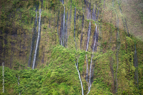 Slender waterfalls cascade down a lush Hawaiian cliff photo
