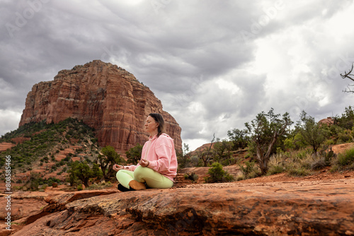 Woman meditating under stormy looking sky sitting on mountain