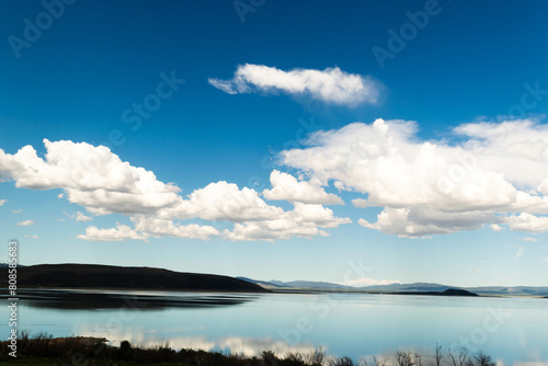 Tranquil lake scene with vivid blue sky and fluffy clouds 