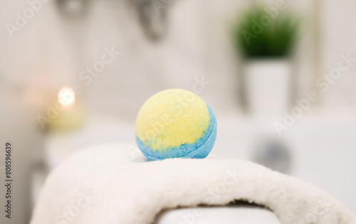 Close-up of yellow scented ball bomb in bathroom against the background of modern bathtub. Concept of therapy, relaxation, spa at home. Background with copy space.