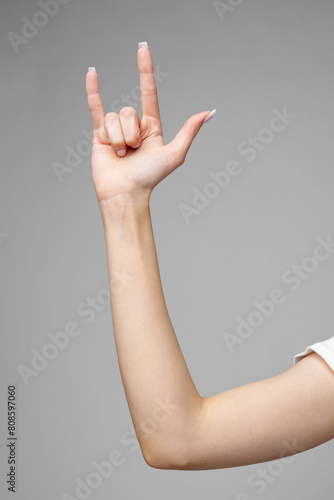 Female hand gesturing sign against gray background