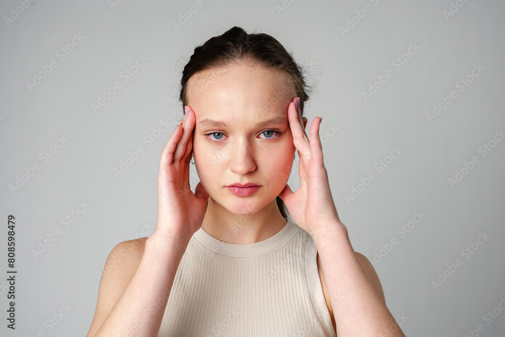 Young Woman Grimacing in Displeasure Against a Neutral Background Young Woman Grimacing in Displeasure Against a Neutral Background