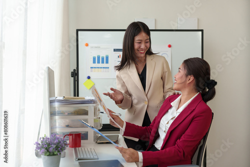 Two happy Asian businesswomen Discuss financial document work starting a business Creative team brainstorming meeting, business partnership or teamwork concept of office colleagues.