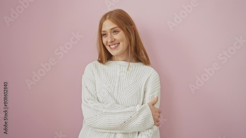 Confident young redhead woman, happily laughing away with a natural expression and a sunny smile. standing in a stylish sweater over an isolated pink background. photo