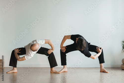 two young athletes practice yoga in the gym. Joint training, indoors, studio. The concept of a healthy lifestyle