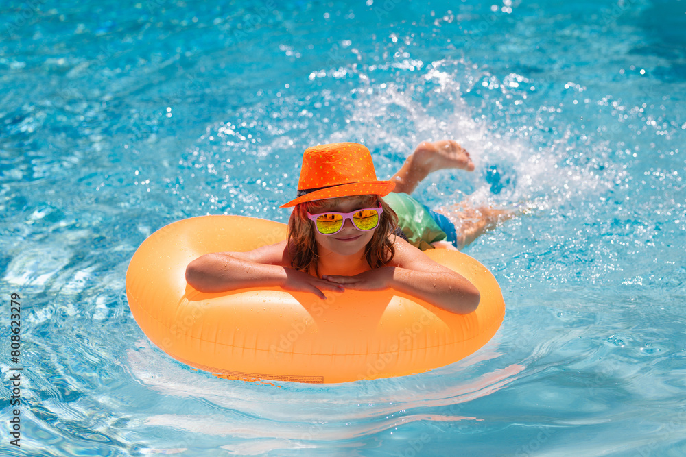 Funny kids summer face. Child swim with float ring in swimming pool. Kids summer holidays and vacation concept. Happy little boy with colorful inflatable ring in swimming pool.