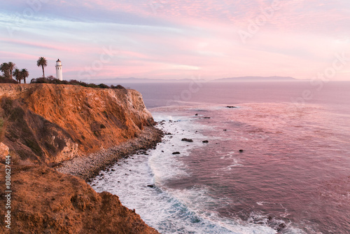Lighthouse stands guard over a pink-hued coastal sunset photo