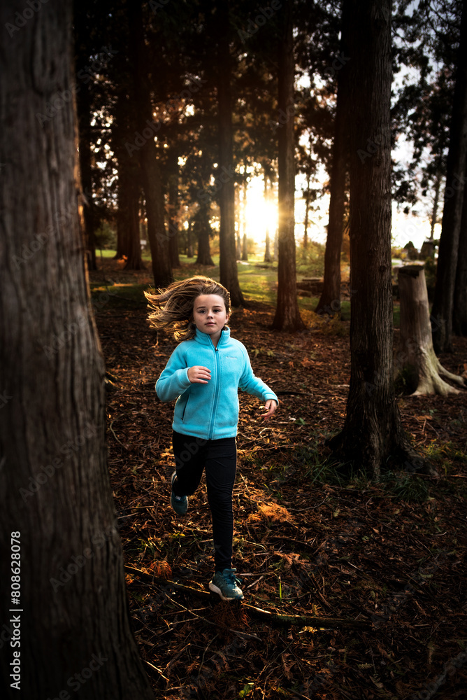 Young girl running through forest at sunset Young girl running through forest at sunset