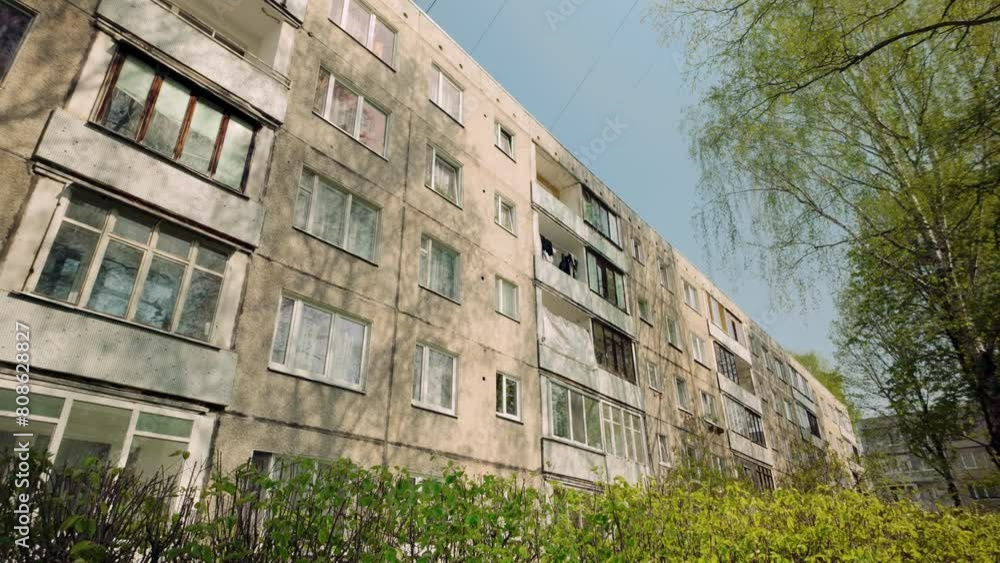 Aged ex soviet apartment block with windows in green spring landscape Aged ex soviet apartment block with windows in green spring landscape
