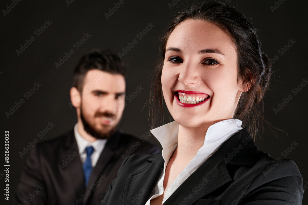 Cheerful professional woman upfront, man slightly blurred Cheerful professional woman upfront, man slightly blurred
