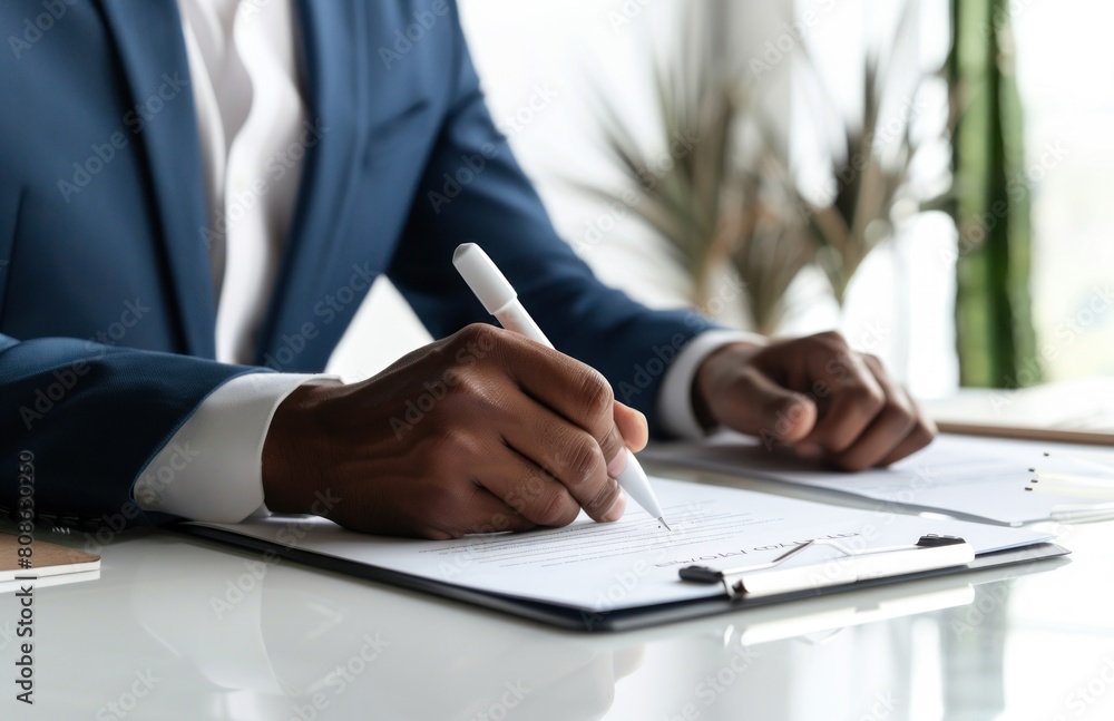 a male businessman with a suit signing a document with his pen by writing down his signature. a male businessman with a suit signing a document with his pen by writing down his signature.