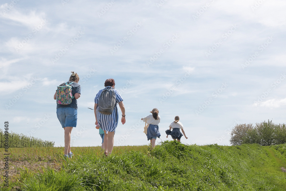 Two middle-aged women walking with children in the countryside