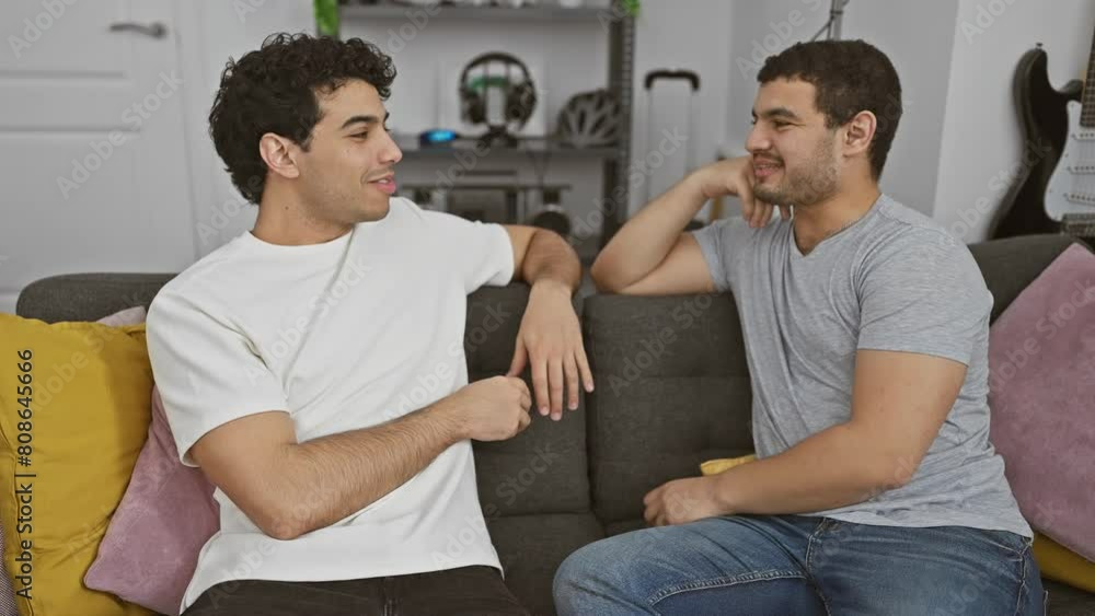 Two men laughing and embracing on a sofa, expressing friendship in a cozy home setting. Two men laughing and embracing on a sofa, expressing friendship in a cozy home setting.