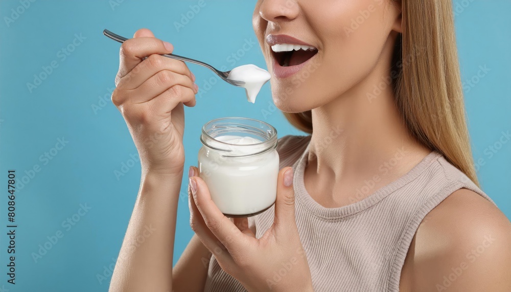 Eating delicious natural yogurt on light blue background Eating delicious natural yogurt on light blue background