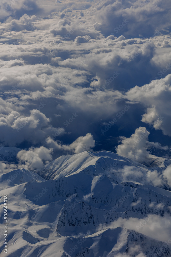 Aerial Airplane Panoramic view white clouds and snowy mountains peaks clear sunny day.Winter vacation. Panorama, banner