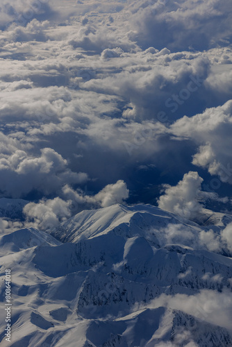 Aerial Airplane Panoramic view white clouds and snowy mountains peaks clear sunny day.Winter vacation. Panorama, banner