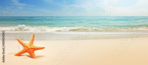 Copy space image of a sandy beach with a handwritten holiday message of Joy accompanied by a textured orange starfish
