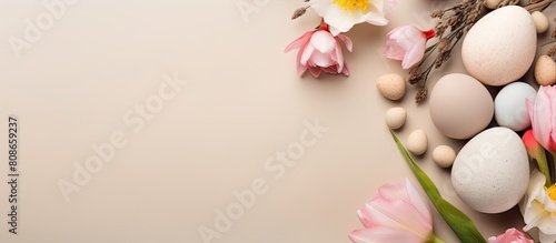A flat lay with Easter eggs flowers and an Easter greeting card on a beige background leaving empty space for copy. Copy space image. Place for adding text and design photo