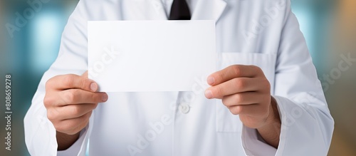 A male doctor confidently showcasing a blank white card providing ample copy space for a personalized message or image