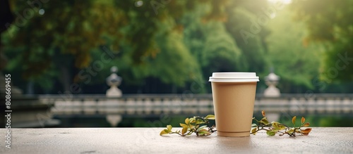 Outdoor copy space image of a coffee to go a cardboard cup with a plastic lid placed on a stone parapet near a fountain