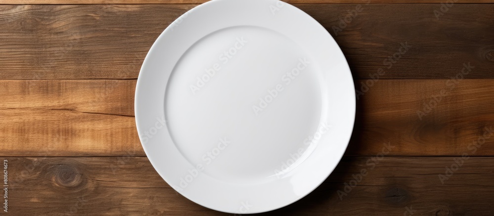 Top view of a white plate mockup placed on a dark wooden table background providing ample copy space for images Top view of a white plate mockup placed on a dark wooden table background providing ample copy space for images