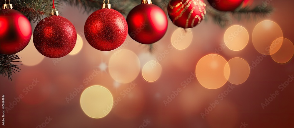 Copy space image of red Christmas balls hanging on pine branches along with tree garland and ornaments against an abstract bokeh background Copy space image of red Christmas balls hanging on pine branches along with tree garland and ornaments against an abstract bokeh background