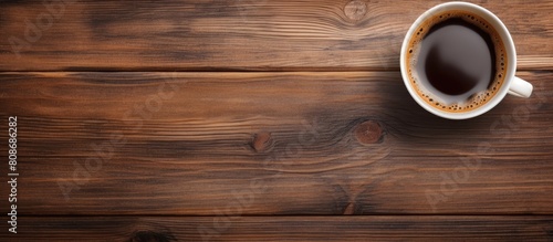 A top view panorama of a cup of coffee sitting on a wooden background with copy space for additional elements