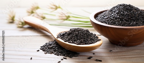 Black cumin also called Nigella sativa seeds kalo jeera kalonji and black caraway are displayed in an iron scoop and mortar on a white wooden background with ample copy space