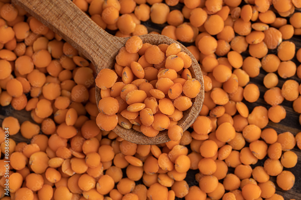 Photo of red lentils in wooden bowl with wooden measuring cup on wooden background. Healthy lifestyle. Vegetarian and vegan diet. Photo of red lentils in wooden bowl with wooden measuring cup on wooden background. Healthy lifestyle. Vegetarian and vegan diet.