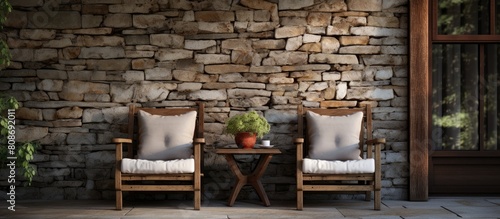 The porch of a home with a wood and stone exterior wall features comfortable chairs adorned with pillows providing a relaxing atmosphere copy space image