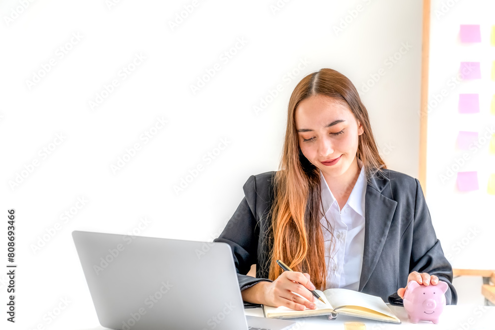 Businesswoman hand writing income and expenses to account with piggy bank and dollar notes, step up start-up businesses to success, Saving money for future plan and retirement fund concept Businesswoman hand writing income and expenses to account with piggy bank and dollar notes, step up start-up businesses to success, Saving money for future plan and retirement fund concept