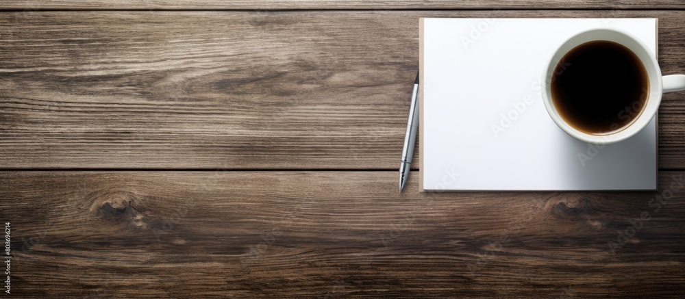 On a wooden table there is a pen paper and a coffee mug creating a visually appealing copy space image On a wooden table there is a pen paper and a coffee mug creating a visually appealing copy space image