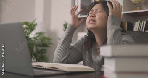 Teenage Asian student, feeling bored and sleepy on campus, seeks solace in cyberspace for education, delving into academic books to reignite their interest in learning. learning and depression. photo