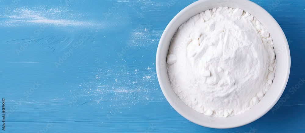 A top down view of a white bowl containing Ural food clay a white clay powder on a blue background The image is isolated and has no people with empty space available for text or other additions A top down view of a white bowl containing Ural food clay a white clay powder on a blue background The image is isolated and has no people with empty space available for text or other additions